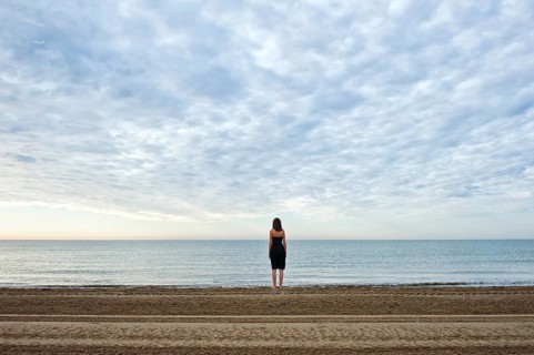 Woman wearing a black dress standing by the sea