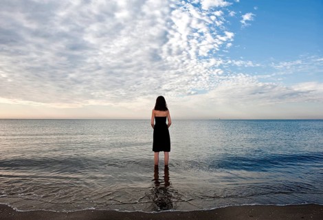 Woman wearing a black dress standing in the water of the sea
