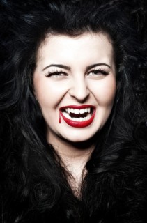 Young Woman dressed as a vampire with blood on her red lips