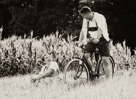 Man and a woman wearing traditional costume with an old bicycle within a natural landscape