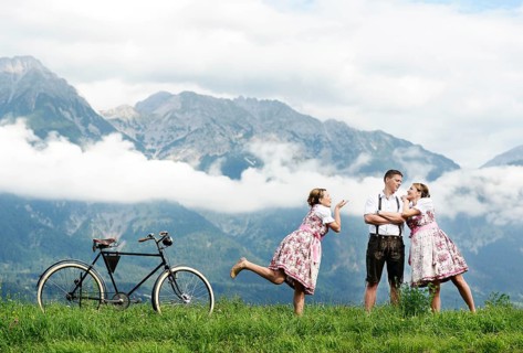 Man and a woman wearing traditional costume with an old bicycle within a natural landscape
