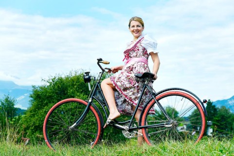 Woman wearing a dirndl on an old bicycle