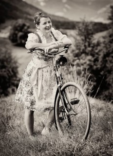 Woman wearing a dirndl with an old bicycle