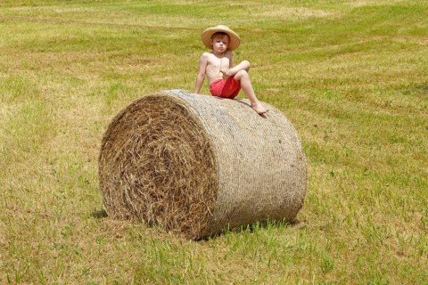 Boy sitting on a bale of straw