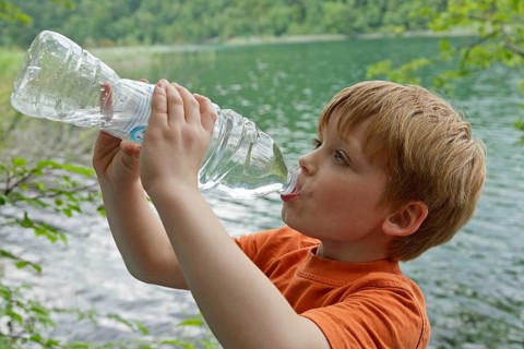 Boy drinks water from a plastic bottle