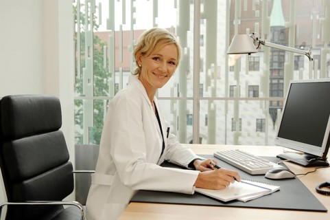 Female doctor in white coat sitting at her desk