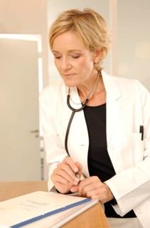 A female doctor in a white coat with stethoscope is standing at a reception desk