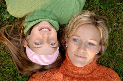 Mother and daughter lying head to head on the grass