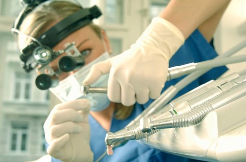 Dentist wearing magnifying loupes preparing a drill