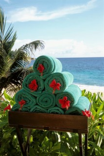 Stack of rolled towels with red flower on the beach