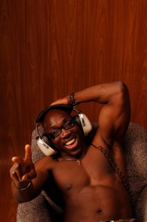 Young muscular bare-chested man sitting in an armchair with headphones