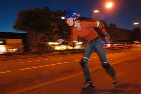 Woman on inline skates wearing a helmet and lights at night
