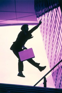 Man wearing a suit and holding a briefcase as a silhouette jumping with a hand held up in the air