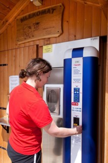 Woman extracting fresh milk from a milk vending machine in Novo Mesto