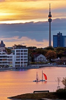 Two sailboats on Phoenix-See lake with Hoerder Burg Castle and Florian Tower at sunset