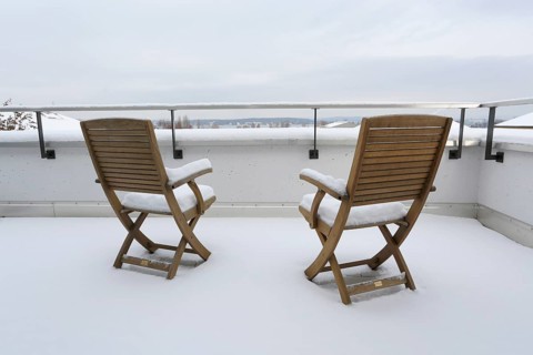 Two snow-covered chairs on a terrace