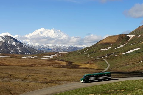 A shuttle bus crossing the Denali National Park and Preserve with views of Mt McKinley at back