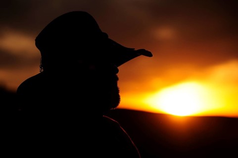 Silhouette of a cowboy in profile looking towards the sunset