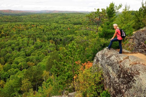 Female hiker standing on a rock overlooking woodlands