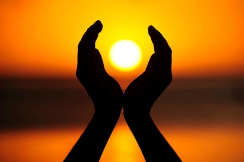 Two hands holding the setting sun