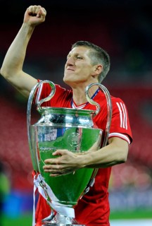 Bastian Schweinsteiger cheering jubilantly while holding the trophy