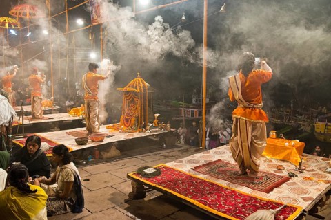 Four Brahmins swinging incense burners during a puja ceremony on platforms at the shore in honour of the Mother Goddess Ganga