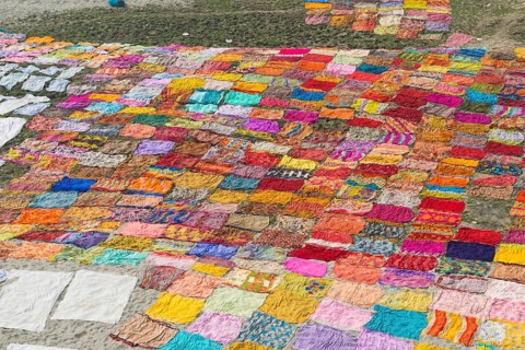 Colourful saris laying to dry after washing on a sandbank on the banks of the Yamuna River