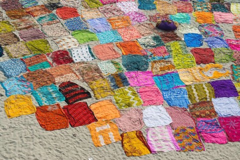 Colourful saris laying to dry after washing on a sandbank on the banks of the Yamuna River