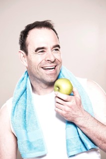 Man with a towel around her neck holding an apple