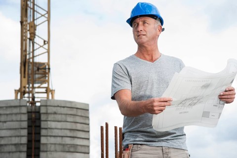 Construction worker wearing a hard hat and holding a building plan
