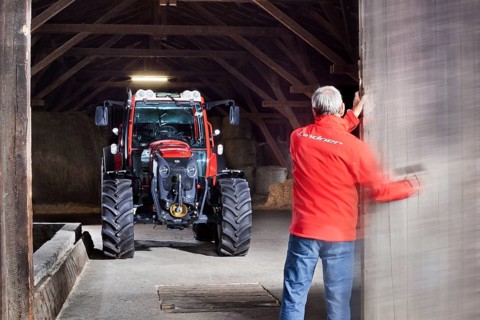Farmer opening a barn door revealing a tractor behind it