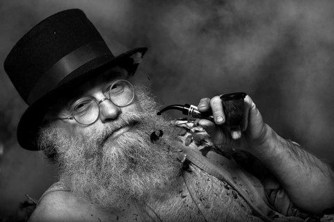 Elderly man with a long beard wearing a top hat and glasses