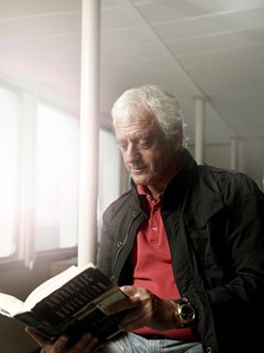 Elderly man reading a book on a ship
