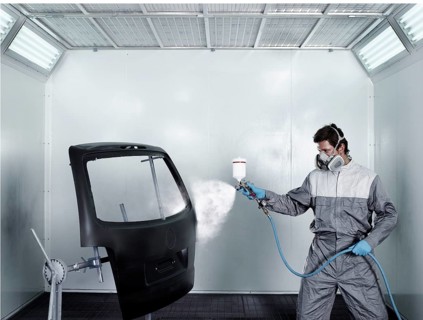 Worker spray-painting the door of a car boot