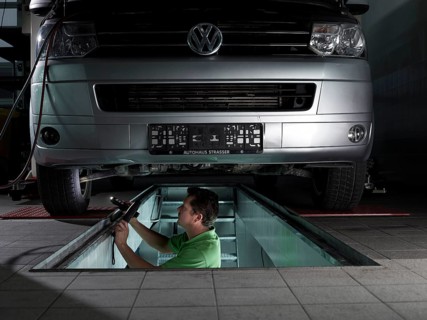 Mechanic standing in a pit checking the brake discs of a VW transporter