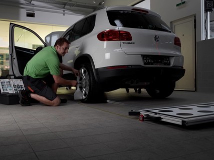Car mechanic taking axis measurements with a laser