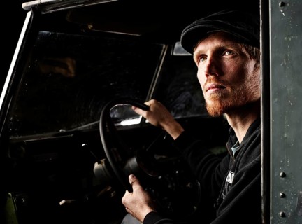 Man with a hat sitting in the driver's seat of an old car