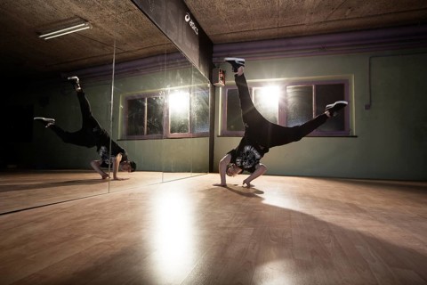 Breakdancer dancing in front of a mirror wall