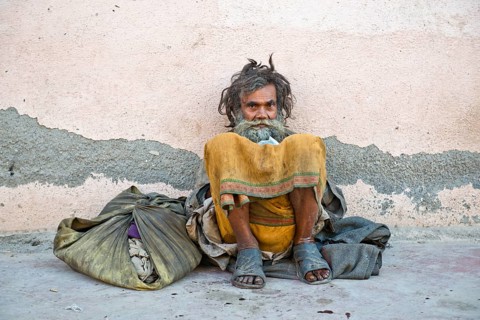Beggar leaning against a house wall