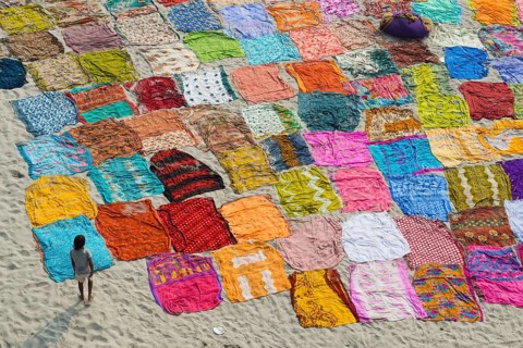 Colourful saris laying to dry after washing on a sandbank on the banks of the Yamuna River