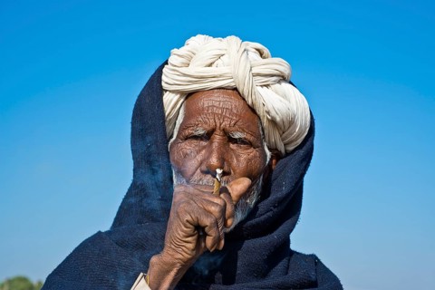 Indian man with a white turban smoking a bidi cigarette