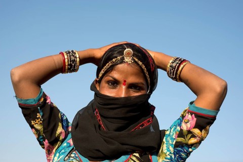 Young Indian woman with jewellery and a bindi covering her face with a black veil