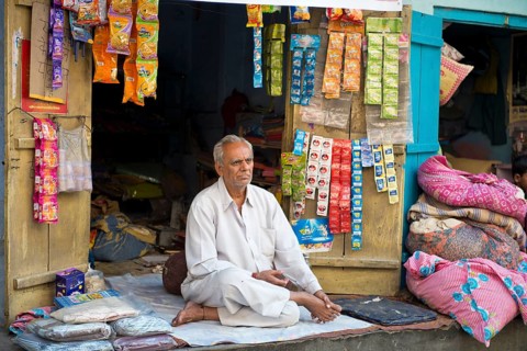 Senior Indian man sitting on a blanket in front of his stall