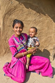 Friendly smiling girl in traditional dress holding a small boy in her arms
