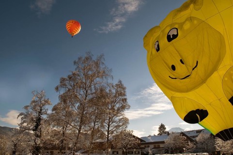 Red hot air balloon travelling against a blue sky