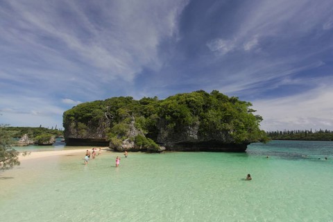 Tourists bathing in front of the sacred rock on the Ile des Pins