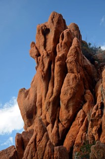 The typical bizarre red rocks of the Calanche of Piana below a blue sky and some clouds. The Calanche of Piana is in the western part of the island Corsica