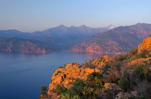 The typical bizarre red rocks of the Calanche of Piana and the mediterranean sea at the Gulf of Porto in the background. The Calanche of Piana is in the western part of the island Corsica