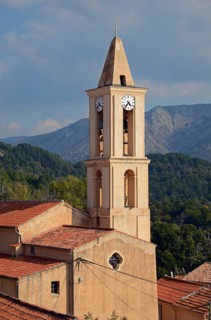 The church of the small village Evisa illuminated by warm evening light surrounded by mountains. Evisa is in the department Corse-du-Sud