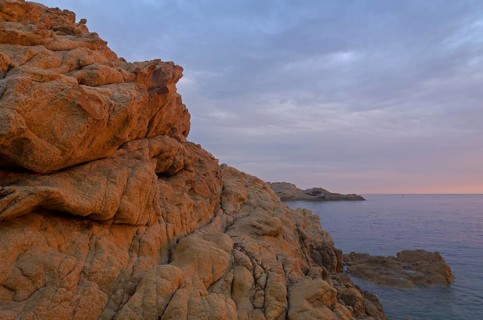 The red granite rocks of the island Ile de la Pietra near L'Île-Rousse illuminated by the first light of the day. L'Île-Rousse  is in the department Haute-Corse
